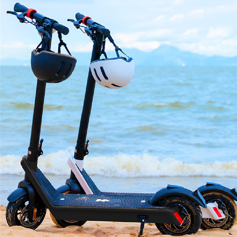 Two electric scooters with helmets on a beach with ocean and sky in the background