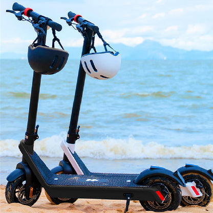 Two electric scooters with helmets on a beach with ocean and sky in the background